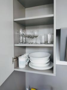 a cupboard with plates and bowls and glasses at Apartamenty Ustroń Jaszowiec 92 abc in Ustroń