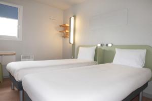 two beds sitting next to each other in a room at ibis budget Goussainville Charles de Gaulle in Goussainville