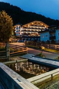 a hotel with a pond in front of a building at Hotel Cesa Tyrol in Canazei