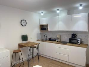 una cucina con mobili bianchi e un orologio sul muro di MW 7A Apartament a Rzeszów
