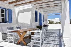 a patio with a wooden table and white chairs at Spacious veranda, house for 3, in the village. in Kamari