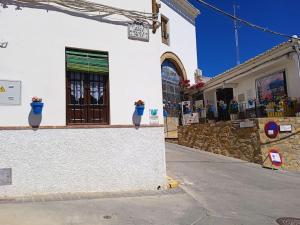 a building with potted plants on the side of a street at Casa de las Campanans in Iznájar