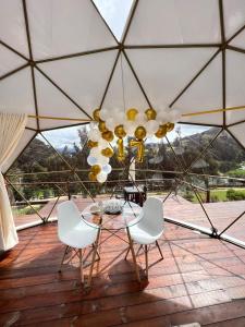 a glass table and chairs on a patio with a chandelier at Golden Glamping in Guatavita