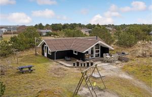 une petite maison noire avec une table et un banc dans l'établissement Beautiful Home In Fan With House A Panoramic View, à Fanø