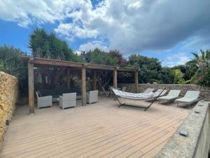 eine Holzterrasse mit Stühlen und einer Hängematte darauf in der Unterkunft Dar Dragun: luxury 3BR bright spacious house & pool in San Lawrenz