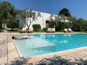 un homme se posant dans l'eau d'une piscine dans l'établissement Agriturismo Terra Rossa, à Otrante