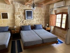 a bedroom with two beds and a ceiling fan at Dar Dragun: luxury 3BR bright spacious house & pool in San Lawrenz
