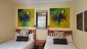 two beds in a room with paintings on the wall at Caribbean Estates Montego bay 30 in Port Edward