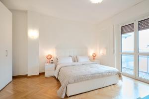a white bedroom with a large bed and two windows at Lux 180sqm flat - entire last floor in Milan