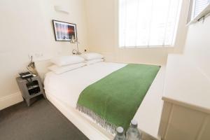 ダブリンにあるケリーズ ホテルのベッドルーム(白いベッド、緑の毛布付)