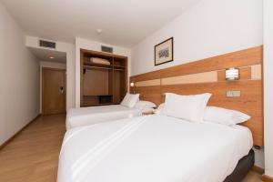 two beds in a hotel room with white sheets at Hotel Faranda Los Tilos in Teo