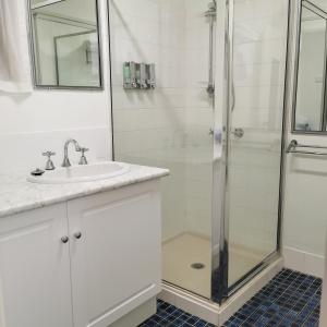 a white bathroom with a shower and a sink at Gallery Motel in Murwillumbah