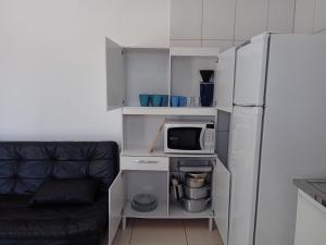 a small kitchen with a microwave and a refrigerator at Chalés Jussara in Ubatuba