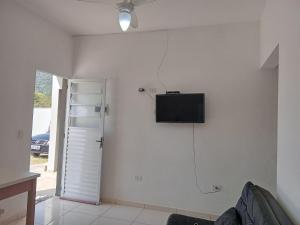 a living room with a tv on the wall at Chalés Jussara in Ubatuba