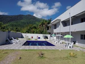 een uitzicht op een gebouw met een zwembad en tafels en stoelen bij Chalés Jussara in Ubatuba