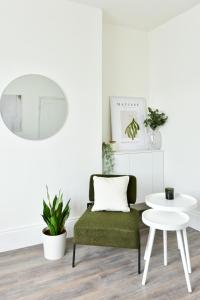 a living room with a green chair and a white table at London Calling 2 bed flat 5 mins train into City. in Winchmore Hill