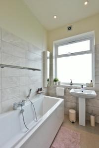 a white bathroom with a tub and a sink at London Calling 2 bed flat 5 mins train into City. in Winchmore Hill