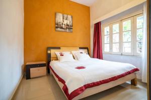 ein Schlafzimmer mit einem großen Bett mit orangefarbenen Wänden in der Unterkunft Aparthotel Madeleine in Antananarivo
