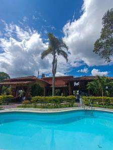 una piscina frente a una casa con palmeras en Hotel del Campo, en Quimbaya