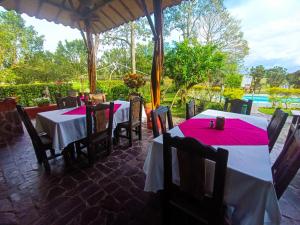 a patio with tables and chairs with red napkins on them at Hotel del Campo in Quimbaya