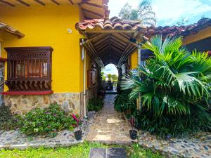 a yellow house with an archway and plants at Hotel del Campo in Quimbaya
