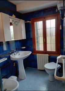 W wyłożonej niebieskimi kafelkami łazience znajduje się umywalka i toaleta. w obiekcie Villa Nadia w mieście Dolo