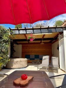 a red umbrella on a patio with a table and chairs at Appartement in Flayosc