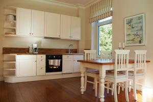 a kitchen with white cabinets and a table with chairs at Villa Baltica - Garten-Appartement in Schönberg in Holstein