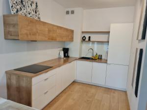 a kitchen with white cabinets and a wooden counter top at ApartamentyPrzyMorzu 010 z Basenem Tarasem i Ogródkiem in Kołobrzeg