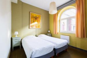 two beds in a room with a window at Domein Tombos in Gingelom