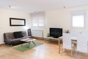 sala de estar con sofá, mesa y TV en La Cueva de Villahormes, en Villahormes