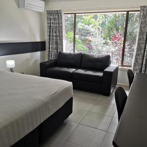 a bedroom with a bed and a couch and a window at Gallery Motel in Murwillumbah