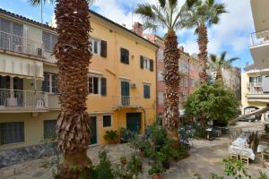 a row of palm trees in a courtyard with buildings at Beau Maison in Corfu