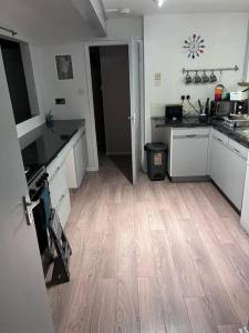 cocina con armarios blancos y suelo de madera en Bay View Retreat, en Paignton