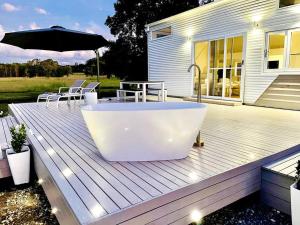 a bath tub sitting on a wooden deck with an umbrella at freed.Omspace in Broken Head