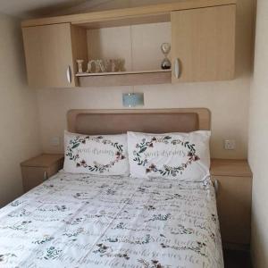 Gorgeous 3 bed static caravan at Hoburne Devon Bay, pet friendly في بينتون: غرفة نوم مع سرير مع وسادتين