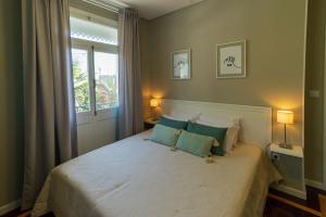 een slaapkamer met een groot wit bed met blauwe kussens bij Blue House in Ponta do Sol +37 foto's
