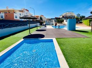 een blauw zwembad met groen gras en gebouwen bij Sunny and Bright Corcovada, T1 with Large Terrace, Albufeira in Albufeira