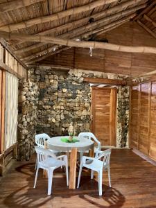 a white table and chairs in a room with a stone wall at Las Cabañas del Rio in Minca