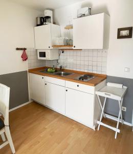 una pequeña cocina con armarios blancos y fregadero en Gemütliche 2 Zi-FeWo mit Terrasse, Strandnähe, WIFI, en Breege