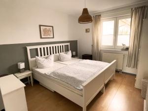 1 dormitorio con cama blanca y almohadas blancas en Gemütliche 2 Zi-FeWo mit Terrasse, Strandnähe, WIFI, en Breege