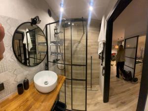 a bathroom with a shower with a sink and a mirror at Przytulny apartament nad morzem - RUSINOWO in Rusinowo