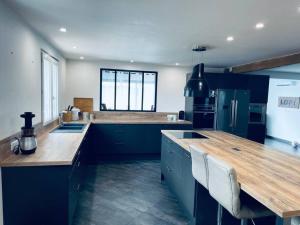 a kitchen with blue cabinets and a wooden counter top at Maison Spacieuse au Calme Piscine Privée in Boudy