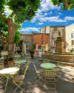 un patio con mesas, sillas y una fuente en Bastidon à Gordes avec piscine, en Gordes