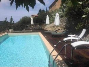 a swimming pool with chairs and umbrellas on a patio at Maison Lama in Lama