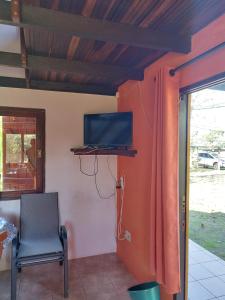 Habitación con TV, silla y ventana. en Mar de Colores, en Punta del Diablo