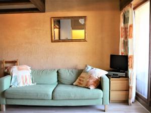 a living room with a green couch and a television at Appartement Auris, 2 pièces, 4 personnes - FR-1-297-65 in Auris