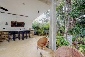 an open kitchen and dining area of a house with trees at Spacious Condo, beautiful pool, Wi-Fi - Casa Kaanal 104 in Tulum