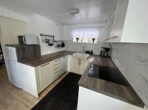 una pequeña cocina con armarios blancos y fregadero en Fully equipped beautiful cottage, en Nora