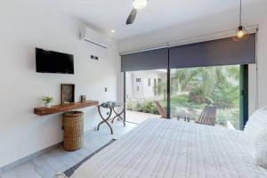 a living room with a tv and a large window at Spacious Condo, beautiful pool, Wi-Fi - Casa Kaanal 104 in Tulum